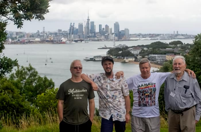 4 men on hill overlooking harbour